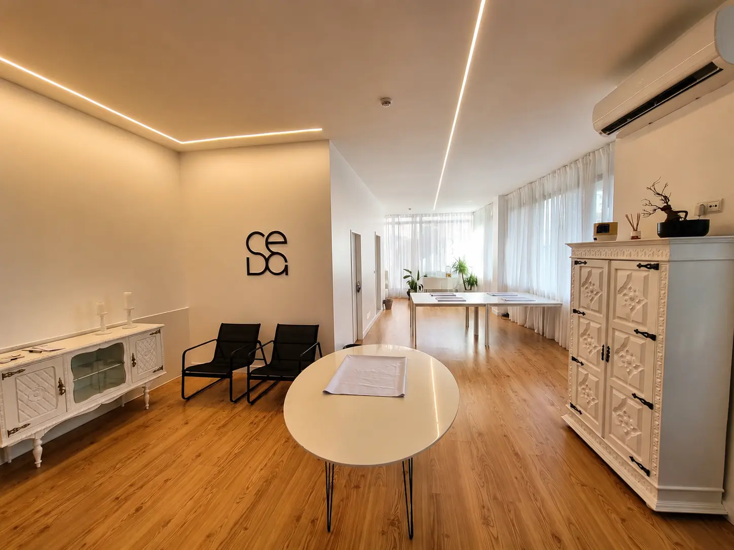 Sala principal da Seda Eventos com pavimento em madeira, luz indirecta e mobiliário branco